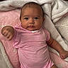 baby, infant, pink_onesie, blanket, soft_texture, hand, cute, reaching_out, lying_down, indoors, skin, face, expression, child, newborn, comfort, warm, cozy, resting, portrait