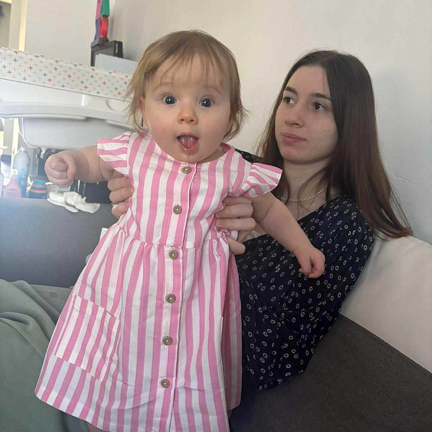Ambre a rejoint le concours — aidez-le/la à gagner de superbes lots ! baby, barefoot, casual_clothing, child, couch, curious, dress, expression, face, furniture, holding, home, indoor, long_hair, person, pink_stripes, seated, skin, sofa, woman