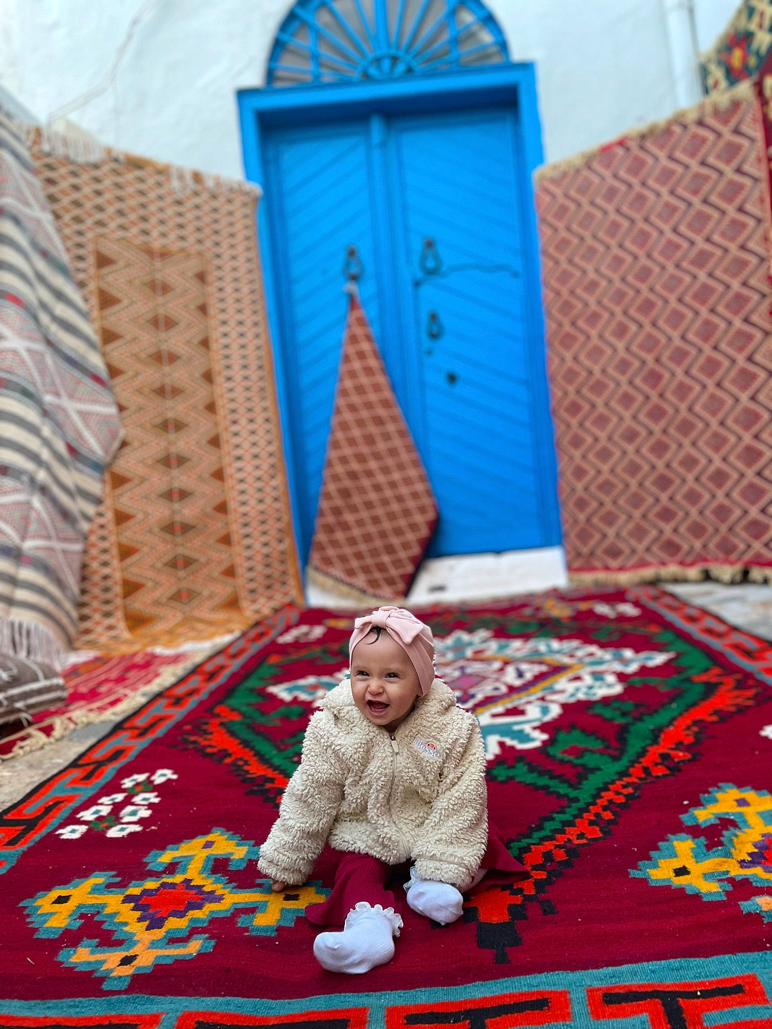 Ayla a rejoint le concours — aidez-le/la à gagner de superbes lots ! baby, blue, carpet, comfort, crawling, door, floor, flooring, grass, headwear, leisure, linens, magenta, pattern, person, red, room, rug, sitting, textile