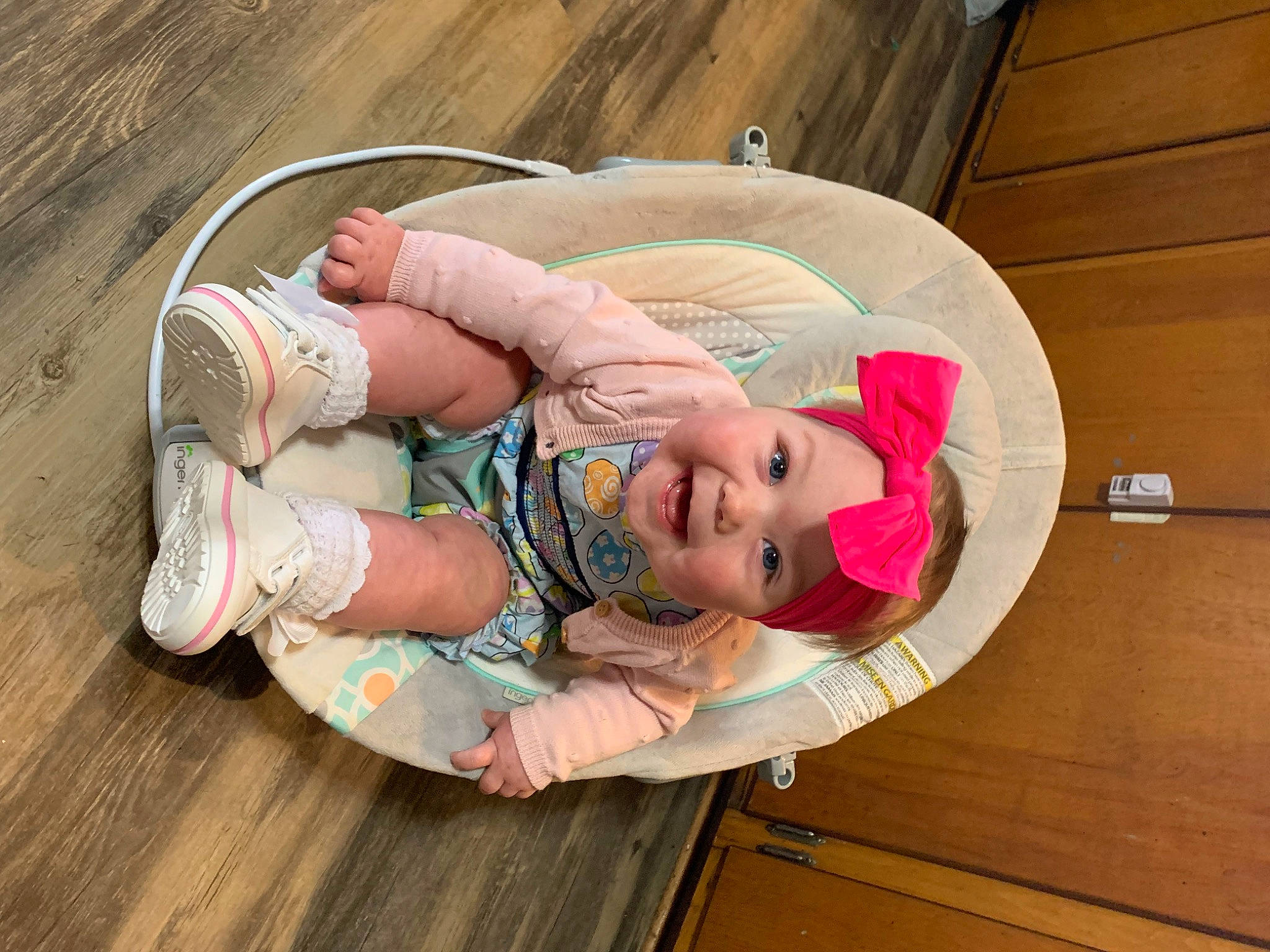 Nova is registered to the contest to win money with this photo: baby, baby_products, baby_safety, baby_toddler_clothing, cheek, child, comfort, flooring, fun, happy, hardwood, headgear, headwear, leisure, pattern, person, pink, sitting, toddler, wood