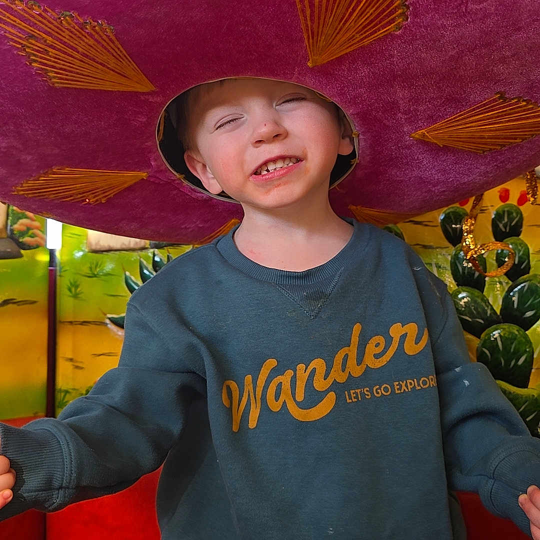 Liam joined the competition — help win amazing prizes! child, smiling, sombrero, hat, blue_sweatshirt, jeans, indoor, colorful, red_couch, greenery, happy, portrait, casual_clothing, young_boy, fun, playful, decor, embroidery, cheerful, kid