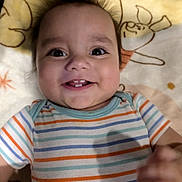 Elijah joined the competition — help win amazing prizes! baby, child, infant, smiling, happy, portrait, close_up, lying_down, blanket, onesie, striped_clothing, cartoon_blanket, bed, indoors, face, eyes, teeth, hands, adorable, photograph