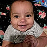Elijah is registered to the contest to win money with this photo: baby, child, infant, smiling, happy, portrait, face, eyes, teeth, sitting, lying_down, toes, hands, gray_shirt, blanket, floral_bedding, bed, indoor, close_up, cozy