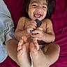 baby, barefoot, bed, blanket, child, closeup, cute, diaper, face, feet, hands, happy, indoor, infant, joy, lying_down, person, playful, smiling, toy_car