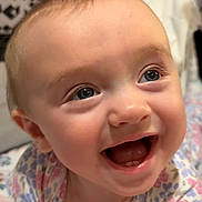 Lilli is registered to the contest to win money with this photo: baby, baby_girl, blue_eyes, cheerful, child, closeup, cute, face, floral_clothing, happy, head, indoor, infant, mouth_open, person, portrait, skin, smiling, teeth, young