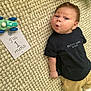 Charly a rejoint le concours — aidez-le/la à gagner de superbes lots ! baby, infant, carpet, toy_car, card, black_shirt, yellow_pants, expression, face, person, lying_down, milestone, one_month, cute, indoor, child, texture, clothing, newborn, portrait
