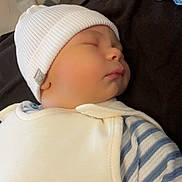 Charly participe au concours pour gagner de l'argent avec cette photo : baby, sleeping, infant, white_hat, striped_clothing, pacifier, blanket, cozy, cute, peaceful, child, resting, soft_lighting, indoors, portrait, newborn, face, apparel, headwear, baby_bib