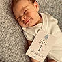 Charly a rejoint le concours — aidez-le/la à gagner de superbes lots ! baby, newborn, smiling, white_clothing, milestone_card, blanket, resting, infant, face, peaceful, portrait, one_week, cute, sleepy, skin, person, lying_down, baby_girl_or_boy, soft_light, indoors