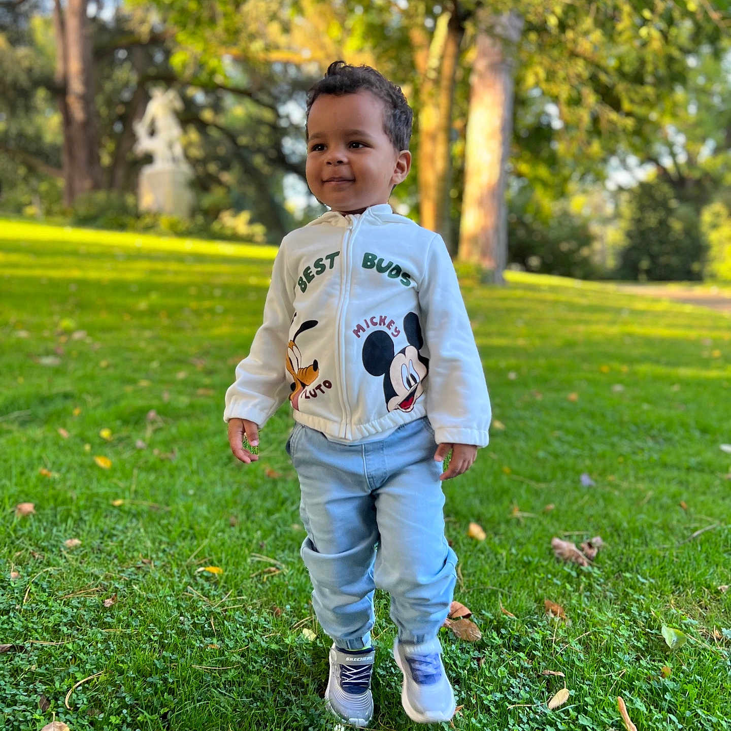 Bogdan participe au concours pour gagner de l'argent avec cette photo : child, toddler, outdoor, grass, trees, sunlight, jacket, mickey_mouse, pluto, sneakers, walking, greenery, park, smiling, person, casual_clothing, nature, daylight, happy, young_child