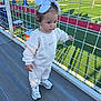 bleachers, casual_clothing, child, daylight, football_field, girl, green_field, nike, outdoor, shadows, sneakers, spectators, sports, stadium, sweatpants, sweatshirt, toddler, white_bows, wire_fence, young_child
