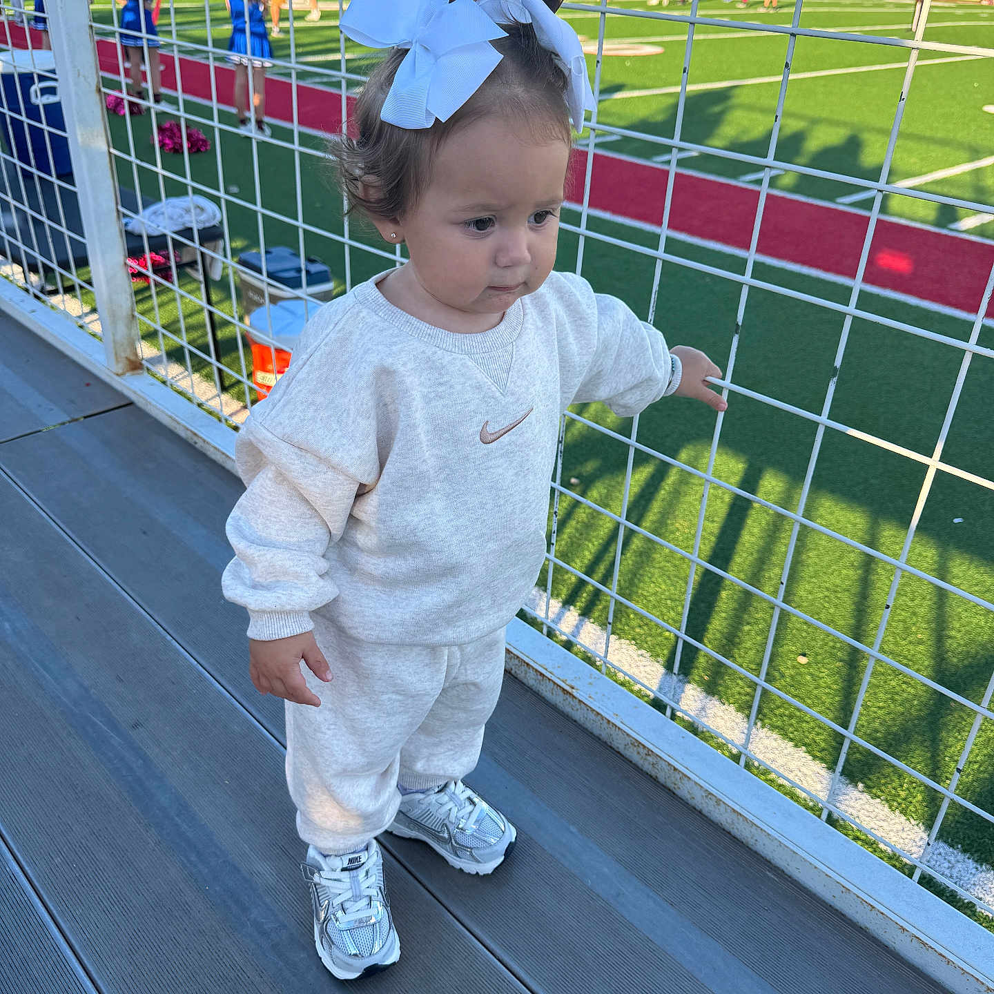 Fallyn joined the competition — help win amazing prizes! bleachers, casual_clothing, child, daylight, football_field, girl, green_field, nike, outdoor, shadows, sneakers, spectators, sports, stadium, sweatpants, sweatshirt, toddler, white_bows, wire_fence, young_child