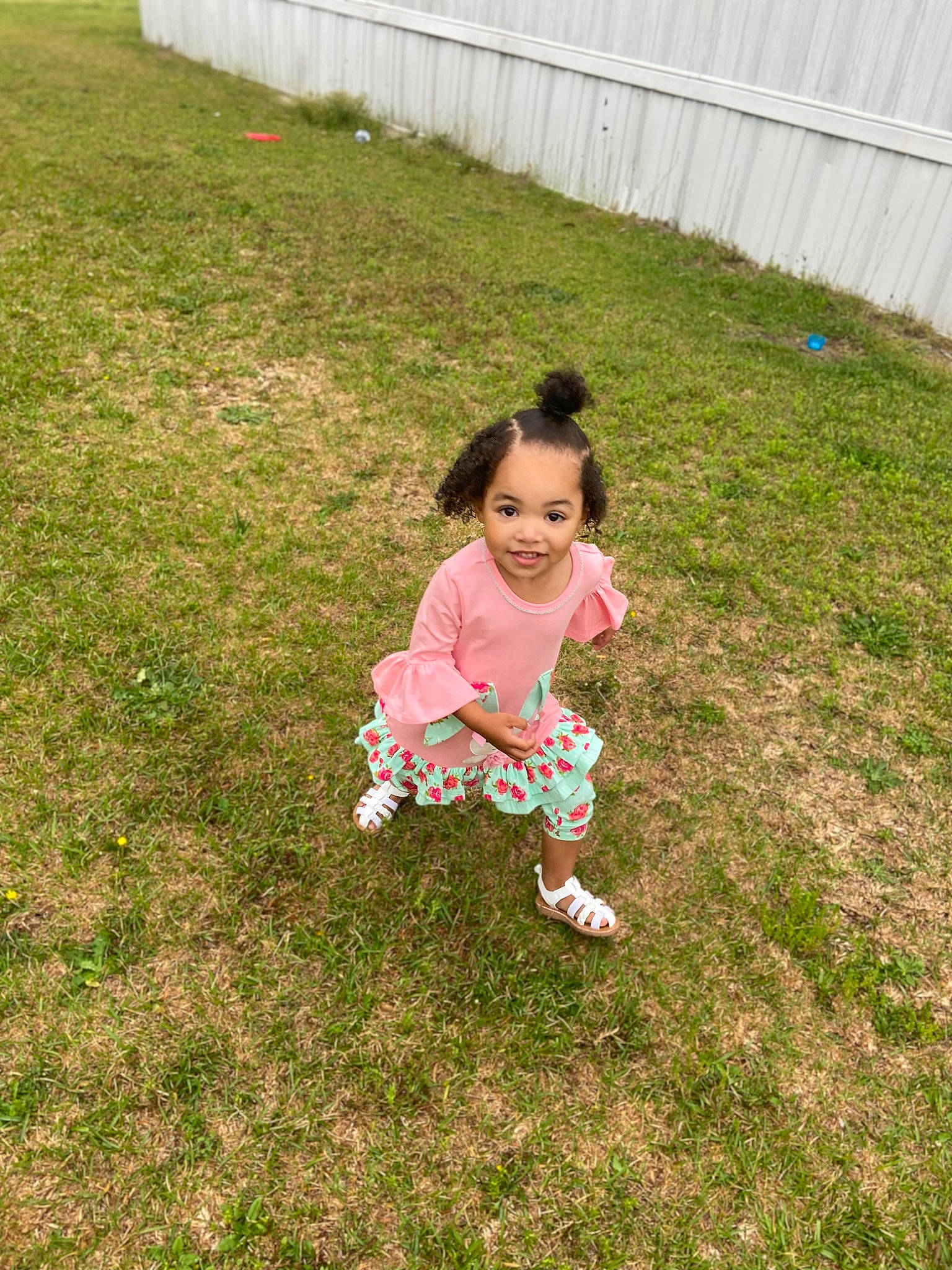 London is registered to the contest to win money with this photo: baby_toddler_clothing, child, fence, fun, garden, grass, grass_family, grassland, groundcover, hair, happy, head, joy, lawn, meadow, people_in_nature, person, plant, recreation, sitting