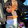black_shirt, car_interior, car_seat, casual_clothing, child, curly_hair, cute, green_shorts, indoor, keys, person, portrait, purple_key_fob, seat, seatbelt, side_profile, sunlight, toddler, white_socks, young_child