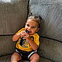 Jayden joined the competition — help win amazing prizes! black_shorts, casual_clothing, child, couch, cute, furniture, happy, home, indoor, natural_light, person, pigtails, playful, remote_control, ribbed_texture, seated, skin, smiling, toddler, yellow_shirt