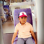Bryan a rejoint le concours — aidez-le/la à gagner de superbes lots ! child, boy, train, seat, cap, spiderman, shorts, casual_clothing, indoor, public_transport, window, curious, sitting, purple_seat, young, person, travel, public_space, portrait, daylight