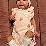 baby, infant, smile, headband, bow, pink_outfit, strawberry_pattern, ruffles, white_socks, plush_cushion, lying_down, portrait, happy, tiny_hands, tiny_feet, soft_texture, nursery, cheeks, dark_hair, legs