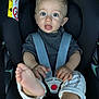 toddler, child, car_seat, seatbelt, feet, blue_eyes, curly_hair, black_car_seat, clothing, baby, sitting, indoors, safety, hands, expression, cute, portrait, infant, casual, straps