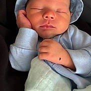 Khari is registered to the contest to win money with this photo: baby, newborn, sleeping, infant, hat, blue_clothing, blanket, hand, face, peaceful, cozy, cute, portrait, closeup, resting, soft, child, indoors, person, calm