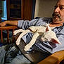 Quinn is registered to the contest to win money with this photo: man, cat, sleeping, chair, wooden_furniture, indoor, casual, mustache, blue_shirt, jeans, relaxed, pet, domestic_animal, resting, comfort, feline, human, home, arm, closeup