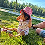 June a rejoint le concours — aidez-le/la à gagner de superbes lots ! toddler, child, pink_hat, outdoor, grass, sunlight, park, tree, blue_sky, coca_cola_bottle, casual_clothing, shorts, sneakers, daylight, nature, sitting, curious, cute, person, summer