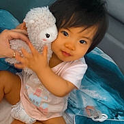 June a rejoint le concours — aidez-le/la à gagner de superbes lots ! toddler, child, stuffed_animal, toy, hand, bed, pillow, blanket, indoor, cute, hugging, soft_toy, infant, clothing, diaper, person, portrait, smile, young_child, cozy
