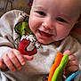 baby, background, bright, child, closeup, clothing, colorful, cute, expression, face, hand, happy, indoor, infant, joyful, person, playful, rainbow, smiling, toy