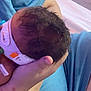 Theodore joined the competition — help win amazing prizes! baby, infant, arm, hand, person, clothing, blue_shirt, newborn, skin, hair, holding, indoor, bed, blanket, comfort, care, rest, closeup, parent, tenderness