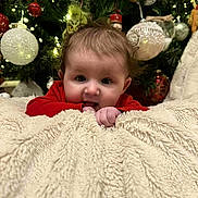 Athena joined the competition — help win amazing prizes! baby, infant, blanket, christmas_tree, ornaments, lights, red_clothing, face, hands, holiday, festive, cute, indoors, soft_texture, chewing, young_child, decorations, holiday_season, christmas, cozy