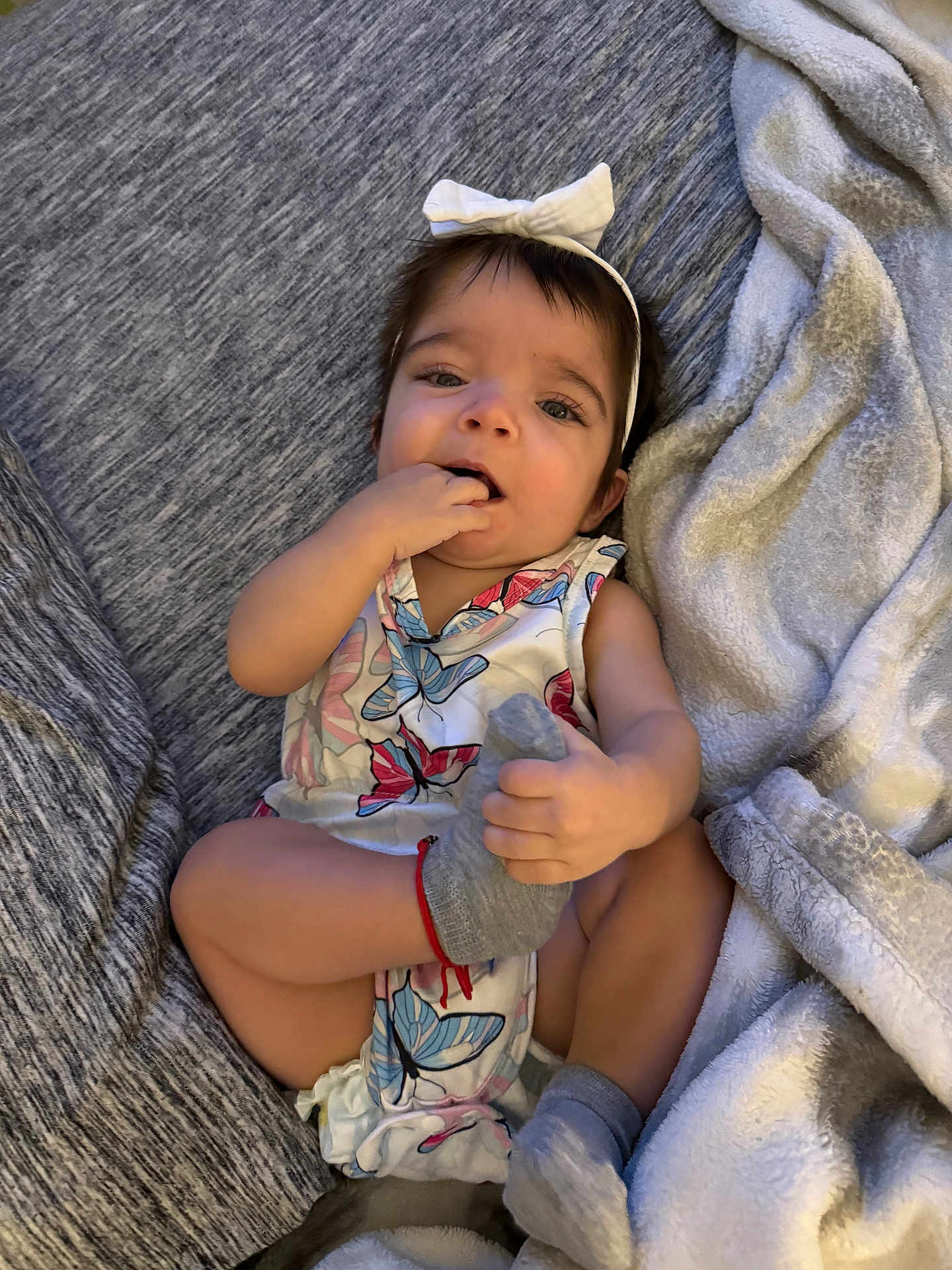 Annaliese joined the competition — help win amazing prizes! baby, child, infant, bow, headband, butterfly_print, sock, hand, foot, blanket, gray, cute, playful, clothing, sitting, indoors, soft_texture, portrait, happy, young