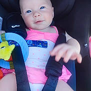 Tilelly participe au concours pour gagner de l'argent avec cette photo : baby, child, car_seat, blue_eyes, pink_clothing, toy, smiling, infant, straps, seatbelt, cute, hand, face, person, sitting, closeup, indoor, young_child, happy, candid