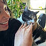 Marceline is registered to the contest to win money with this photo: person, cat, calico_cat, smiling, nose_piercing, hand, nails, indoor, plant, window, natural_light, petting, happy, furniture, black_clothing, face, whiskers, fur, domestic_animal, casual