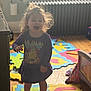 Octavia joined the competition — help win amazing prizes! child, toddler, indoor, barefoot, purple_dress, lion_graphic, foam_puzzle_mats, colorful, hair, radiator, window, wooden_floor, playroom, furniture, smiling, happy, lighting, backlit, person, young_child