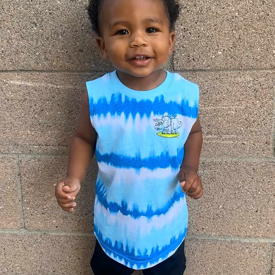 Christofer is registered to the contest to win money with this photo: black_shorts, brick_wall, casual_clothing, child, concrete, cute, feet, happy, outdoor, person, playful, portrait, short_hair, sleeveless_shirt, smiling, sneakers, standing, tie_dye, toddler, urban