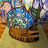 cat, tabby, tail, paws, curtain, floral_pattern, colorful, hiding, playful, indoor, rug, striped, animal, pet, wooden_floor, texture, cozy, home, peekaboo, feline