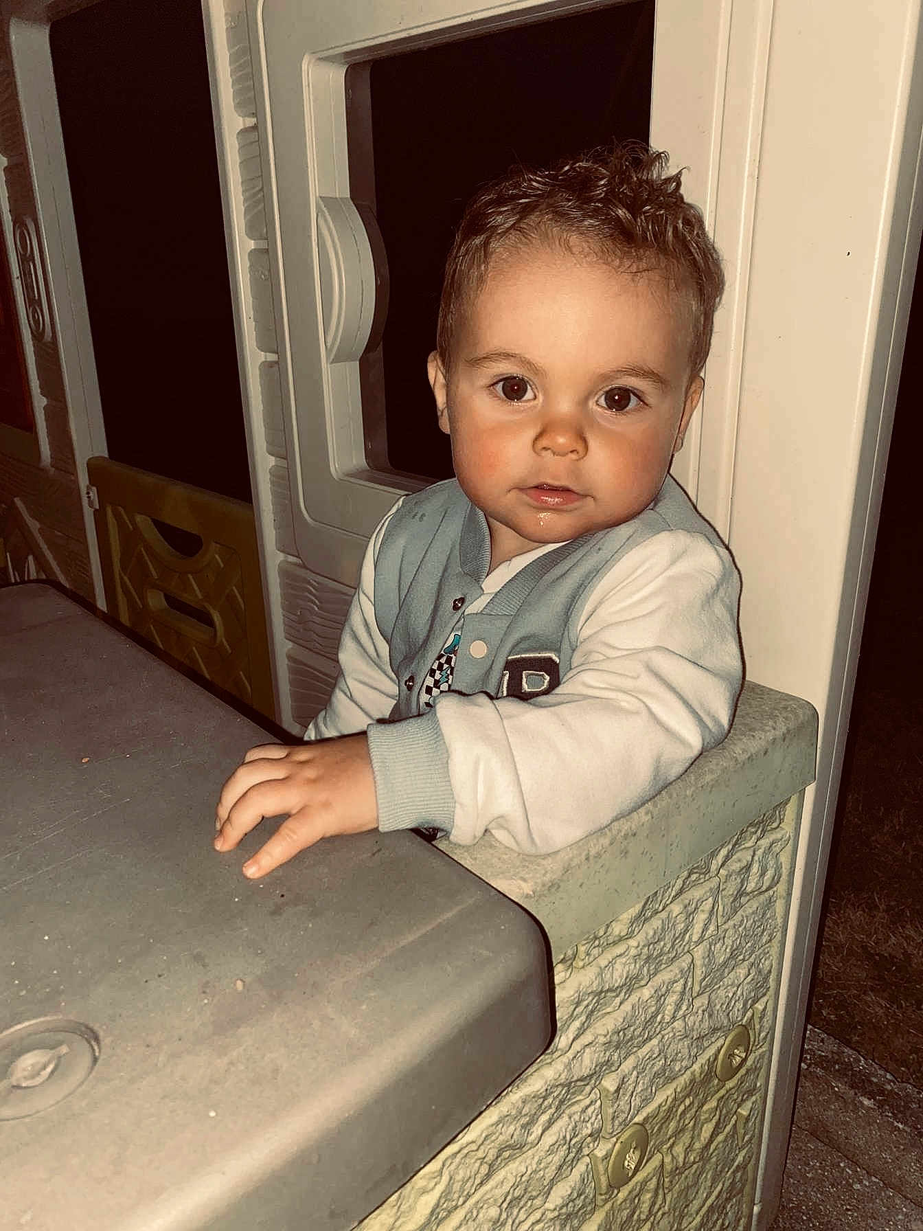 Théo a rejoint le concours — aidez-le/la à gagner de superbes lots ! child, toddler, face, hand, plastic, playhouse, table, jacket, curly_hair, indoors, portrait, looking_at_camera, young_child, casual_clothing, evening, light, play, curiosity, expression, person