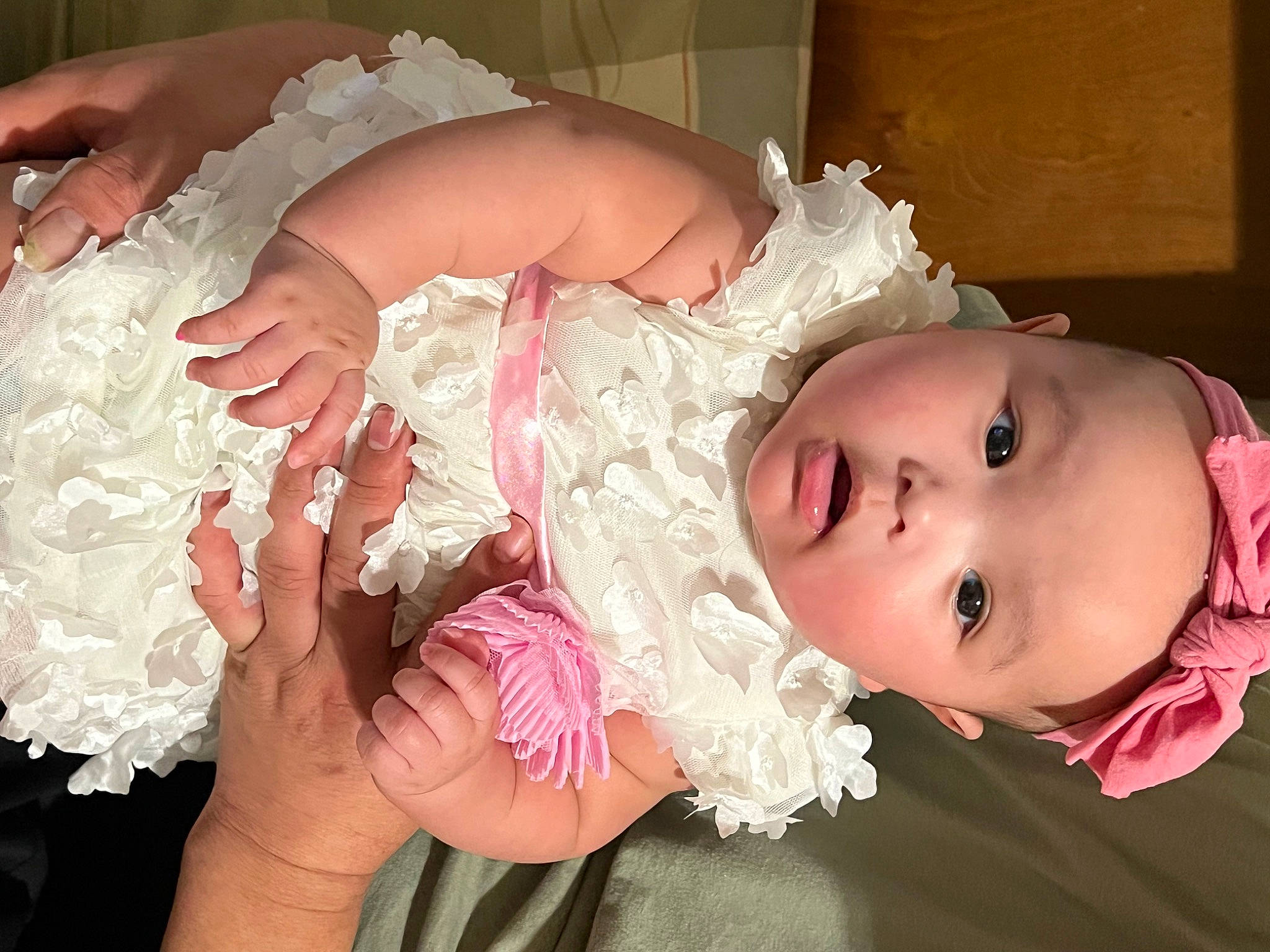 Katie is registered to the contest to win money with this photo: baby, baby_toddler_clothing, bridal_accessory, child, dress, embellishment, hair_accessory, hand, happy, headgear, headpiece, human_body, person, petal, pink, plant, skin, textile, toddler, wedding_ceremony_supply