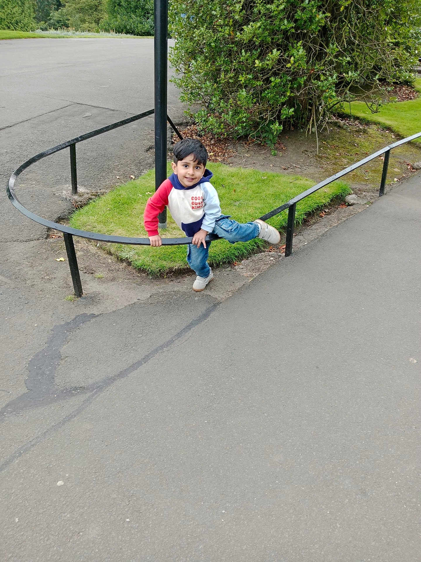 Muhammad joined the competition — help win amazing prizes! child, boy, play, outdoor, park, grass, railing, smile, jeans, sneakers, casual_clothing, greenery, bushes, pavement, fun, young, happy, curved_rail, nature, daylight