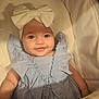 baby, infant, bow, headwear, blue_dress, ruffles, smile, face, eyes, pacifier, bassinet, blanket, soft_lighting, cute, child, portrait, indoors, comfort, sleeping_area, adorable