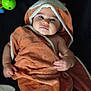 baby, towel, hood, toy, child, infant, cute, lying_down, orange, soft_texture, blanket, plaything, smiling, face, hand, skin, indoors, comfort, rest, young