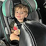 child, toddler, car_seat, car_interior, smiling, cookie, snack, seatbelt, safety, hair, face, leather_seat, window, clothing, cup_holder, seat, seatbelt_strap, happy, young_child, inside_car