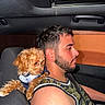 Milo is registered to the contest to win money with this photo: dog, puppy, person, man, car, vehicle, passenger, driver, shoulder, sitting, curly_fur, brown_fur, pet, companion, portrait, indoors, car_interior, seat, seatbelt, photography