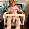 baby, child, infant, high_chair, pink_clothing, headband, butterfly_pattern, smiling, happy, indoor, window, blinds, plant, wooden_floor, modern_furniture, cute, portrait, seated, person, home