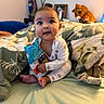 baby, infant, child, toy, soft_toy, bed, pillow, blanket, indoor, person, cute, smiling, sitting, clothing, plush, decor, face, happy, portrait, room