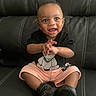 Jay R is registered to the contest to win money with this photo: baby, child, smiling, sitting, black_tshirt, teddy_bear, shorts, black_shoes, leather_couch, happy, clapping, indoor, cute, portrait, person, infant, young_child, expression, casual_clothing, fun