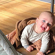 Sacha participe au concours pour gagner de l'argent avec cette photo : baby, child, smiling, blue_eyes, blanket, wooden_floor, indoor, play_mat, cozy, happy, infant, crawling, clothing, person, toddler, cute, warm_light, flooring, portrait, home