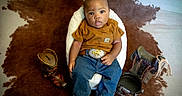 Jasai is registered to the contest to win money with this photo: baby, belt, boots, brown_shirt, chair, child, comfortable, cowboy_boots, cowhide_rug, curious, cute, decor, fashion, footwear, indoor, infant, jeans, person, portrait, sitting
