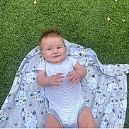 Emelia is registered to the contest to win money with this photo: baby, infant, blanket, sheep_pattern, grass, outdoor, smile, playful, toddler, clothing, cute, lying_down, child, nature, young_child, happy, casual, portrait, baby_girl, baby_boy