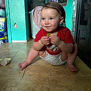 Emelia is registered to the contest to win money with this photo: toddler, child, indoor, floor, grape, red_shirt, diaper, squatting, smiling, cute, baby, tile_floor, hair_wet, expression, person, furniture, laundry_basket, backpack, household, room