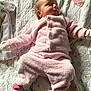 baby, sleeping, pink_clothing, mittens, quilted_bedspread, floral_pattern, bedroom, infant, soft_light, cozy, child, pajamas, newborn, resting, cute, indoor, person, apparel, blanket, peaceful