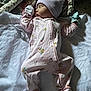 baby, newborn, sleeping, onesie, hat, blanket, quilt, floral_pattern, infant, child, peaceful, soft_lighting, indoors, cozy, cute, portrait, resting, clothing, fabric, bed